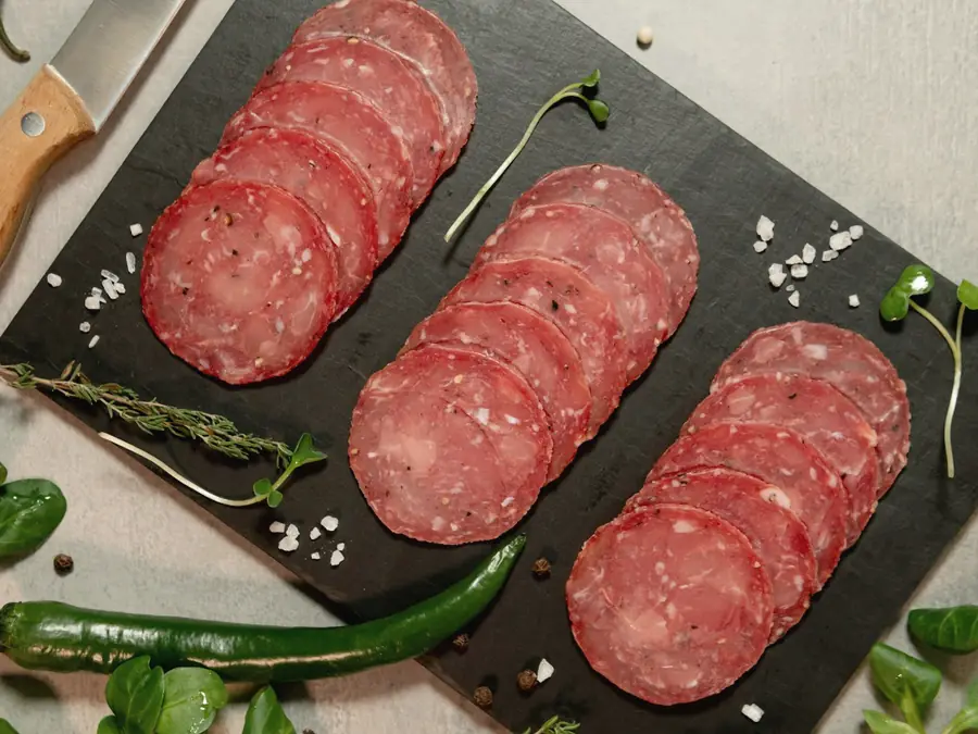 Thin slices of salami on a dark board