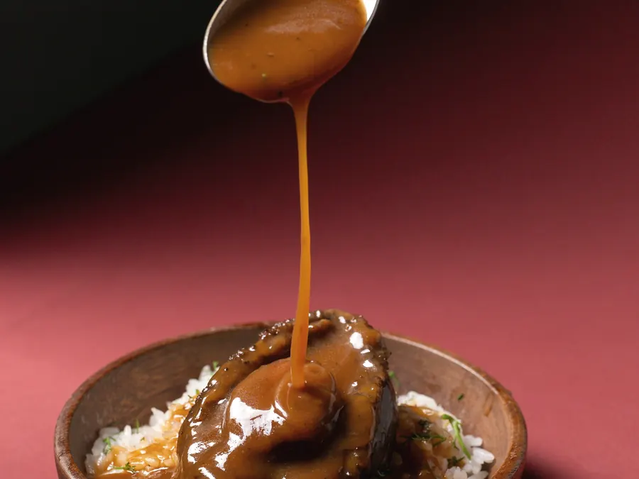 A glossy brown sauce poured from a spoon