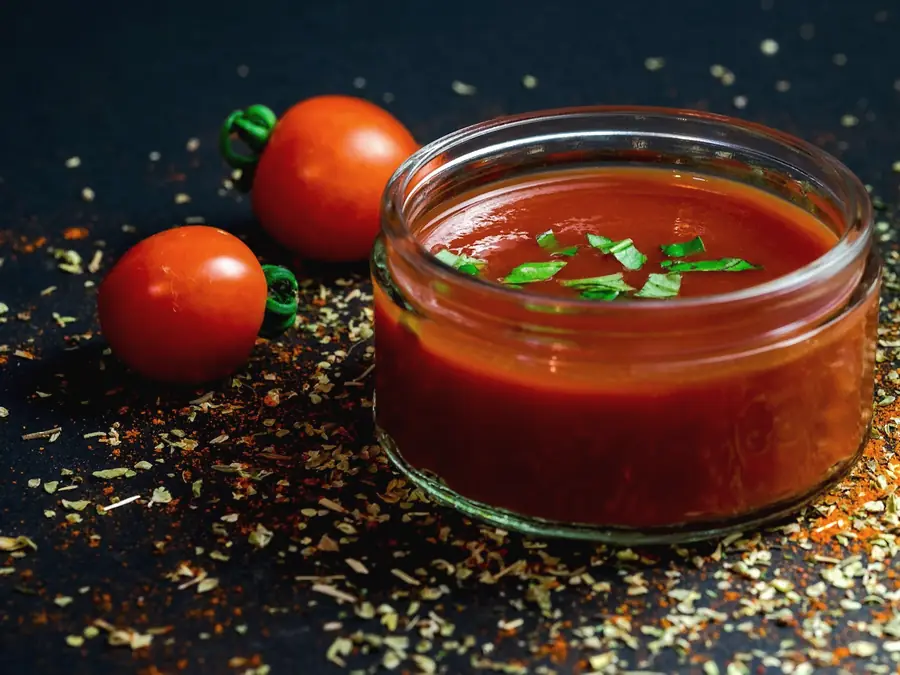 Tomato purée in a bowl beside fresh tomatoes